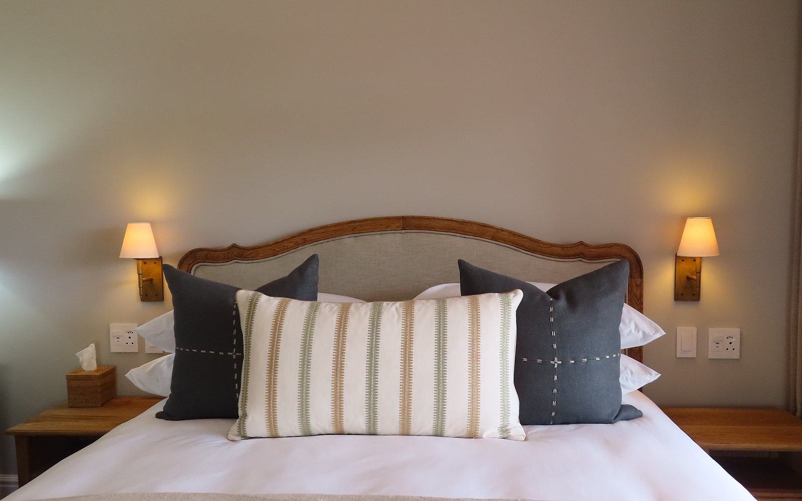 Carved headboard with striped and charcoal cushions in a suite